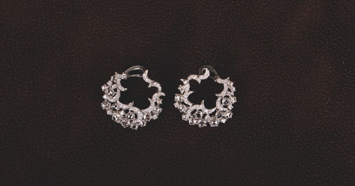 Pair of floral hoop earrings crafted in shimmering lab-grown moissanite jewellery on dark background